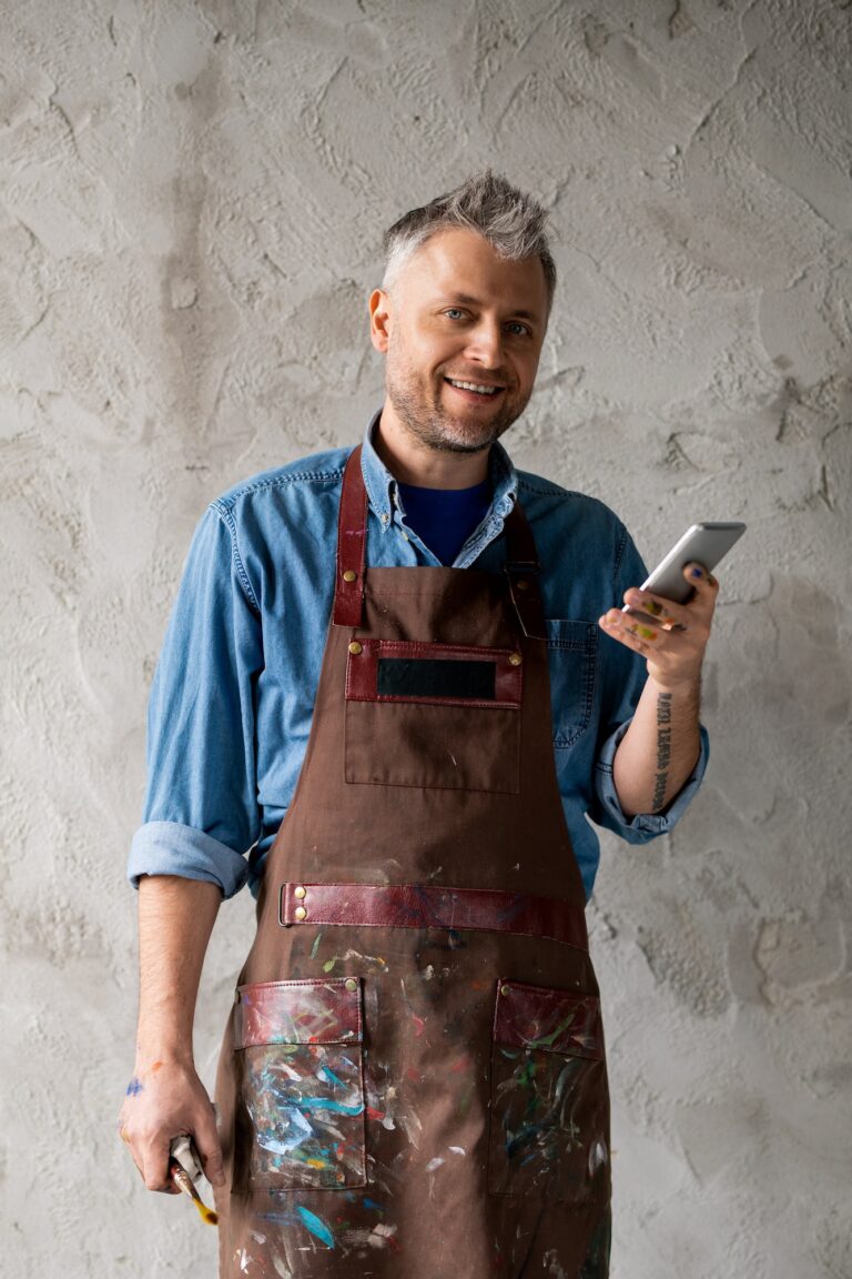 Happy and successful painter with smartphone and paintbrush