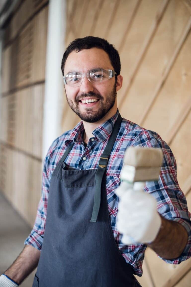 Happy young painter holding paint brush and showing it to camera